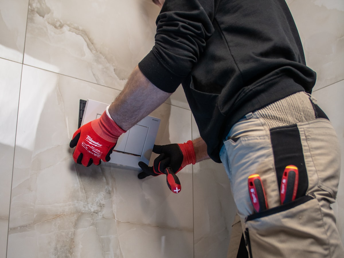 Plumber in gloves fitting a toilet